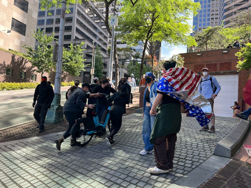 caption: Protesters use e-bikes to block the vehicle exits from the Henry M. Jackson Federal Building on June 10, 2025, hoping to stop trucks carrying detained immigrants from leaving.