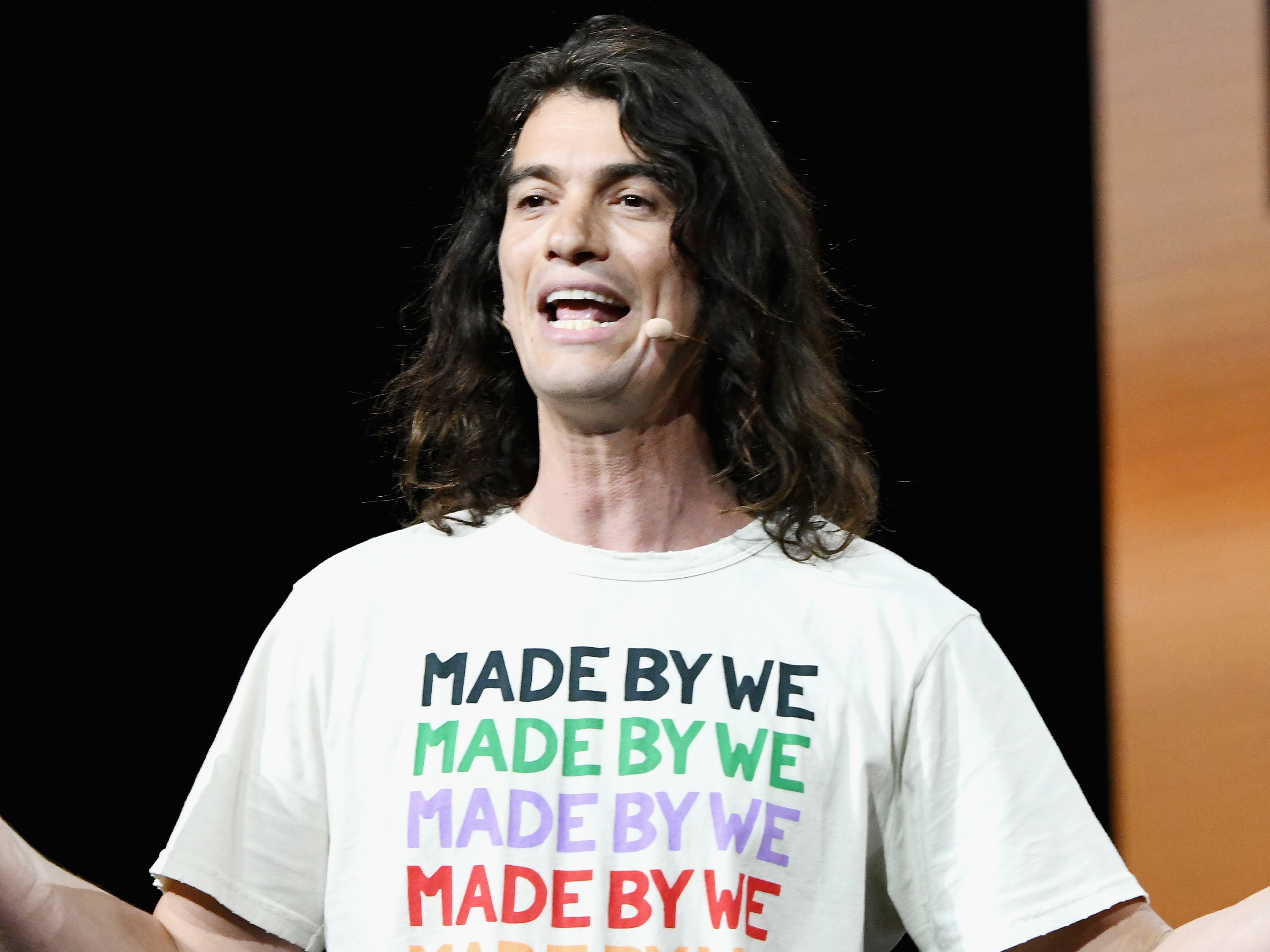caption: Adam Neumann speaks onstage during a WeWork event in 2019.