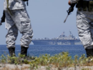 caption: Philippine Navy personnel watch as the U.S. Navy's multipurpose amphibious assault ship USS WASP cruises in the background during the Joint US-Philippine Military Exercise "Balikatan 2019" in April.