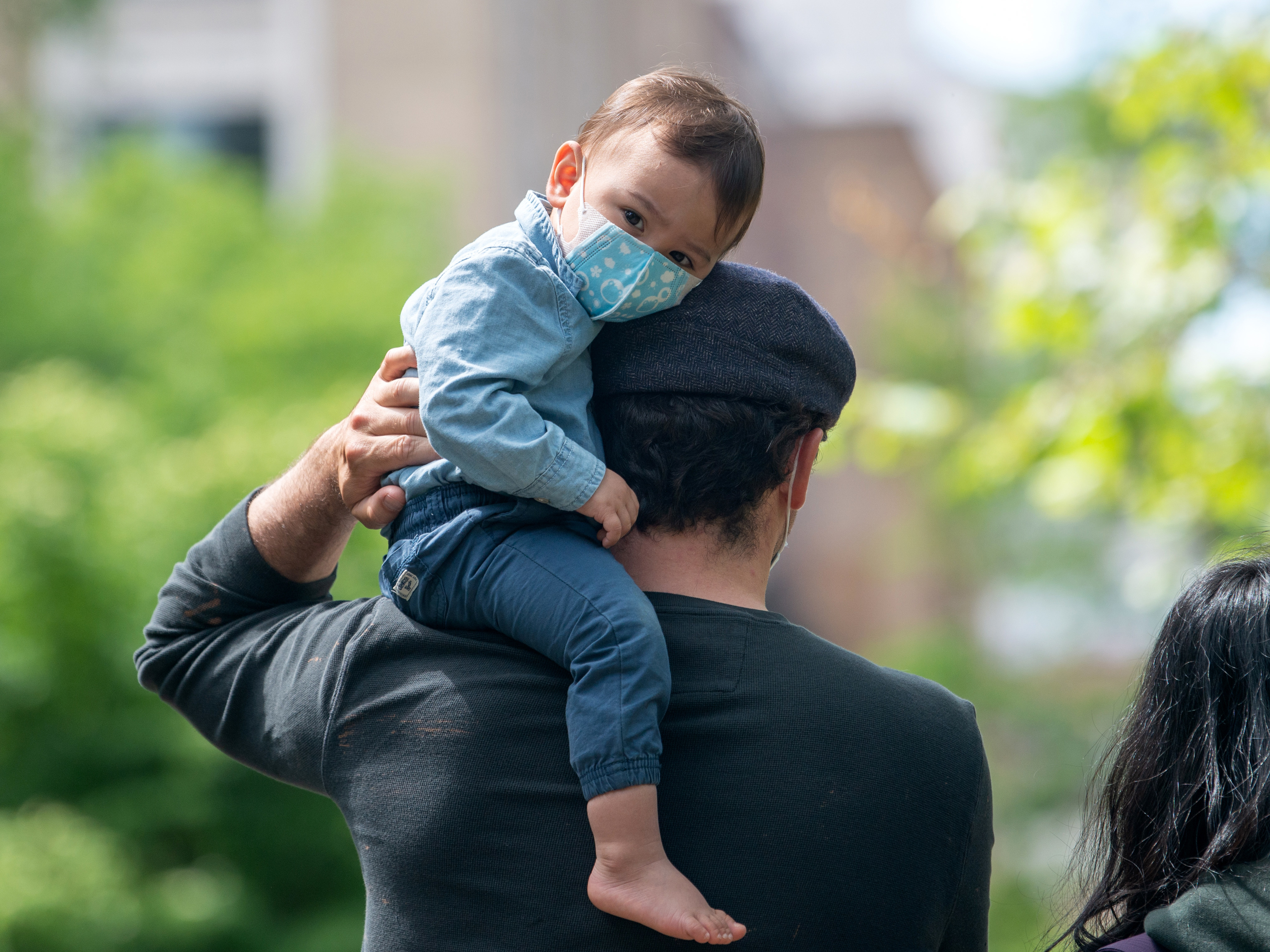 caption: A child wearing a mask sits on his father's shoulder on May 24, 2020 in New York City. Dr. Jose Romero suggested that taking toddlers into the public is a risk.