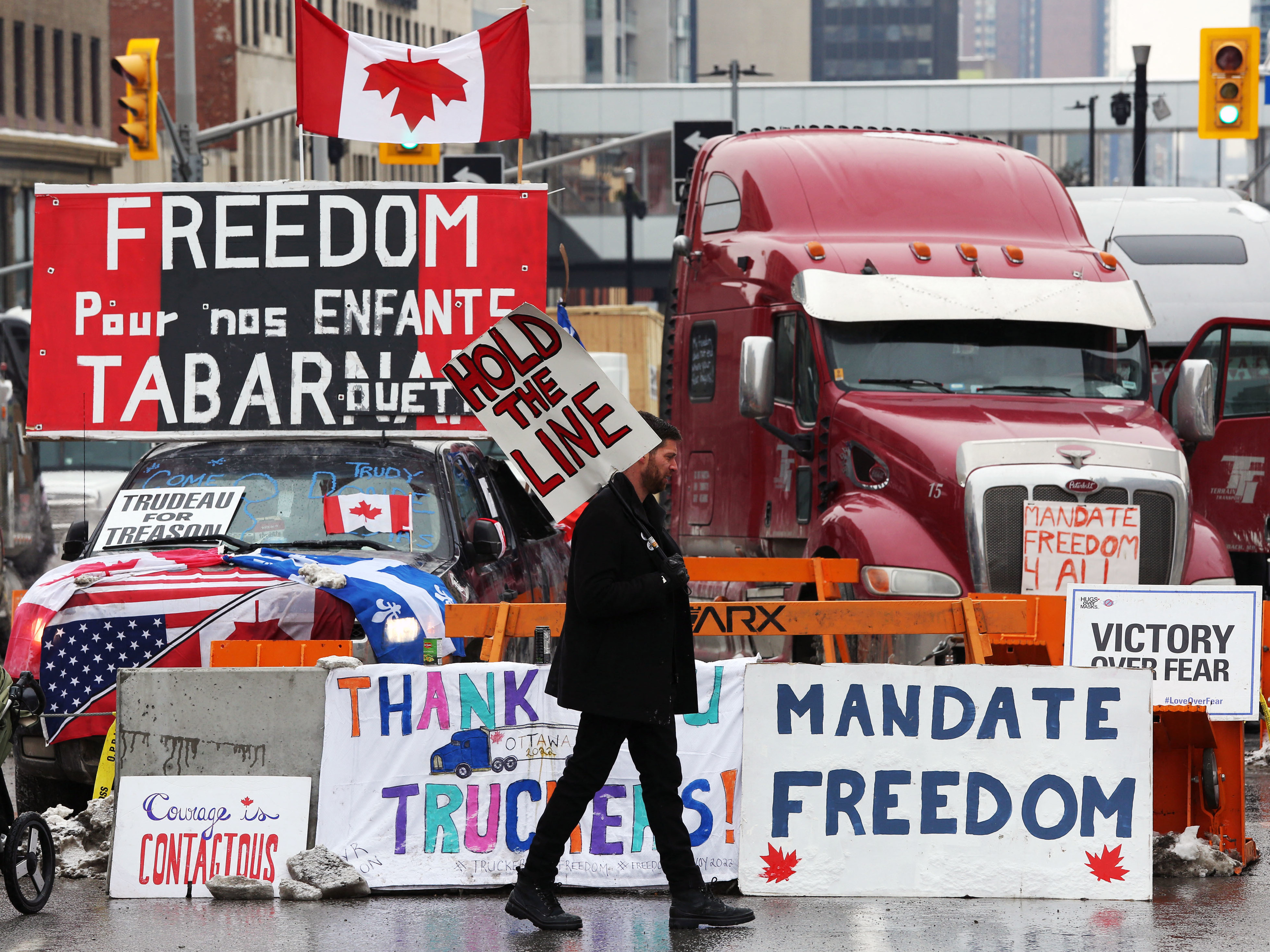 caption: A protester walks in front of parked trucks as demonstrators continue to protest the vaccine mandates implemented by Prime Minister Justin Trudeau on Tuesday in Ottawa, Canada.