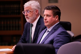 caption: Auburn Police Officer Jeffrey Nelson, center, and defense attorney Tim Leary, behind, attend closing arguments at Maleng Regional Justice Center in Kent, Wash. Thursday, June 20, 2024.