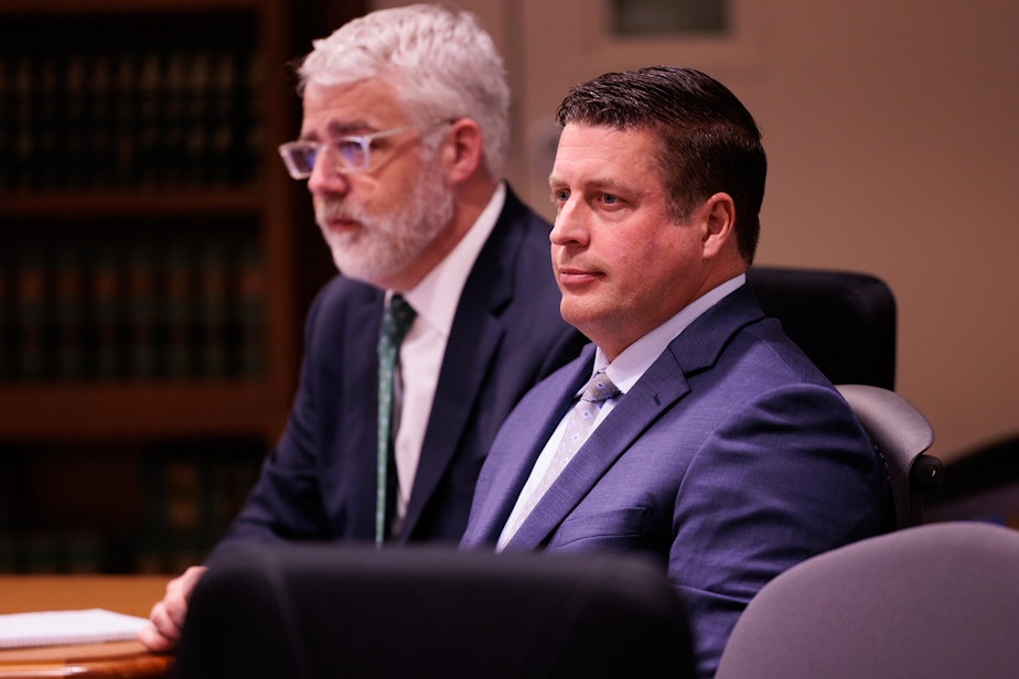 caption: Auburn Police Officer Jeffrey Nelson, center, and defense attorney Tim Leary, behind, attend closing arguments at Maleng Regional Justice Center in Kent, Wash. Thursday, June 20, 2024.