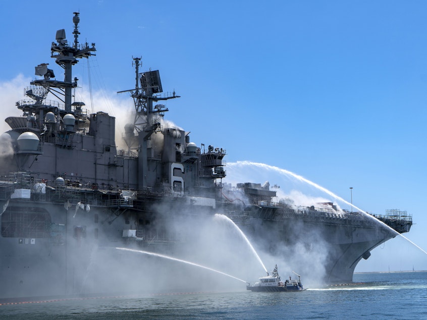caption: Police boats combat a fire aboard the amphibious assault ship USS Bonhomme Richard at Naval Base San Diego on Sunday.