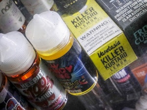 caption: Flavored vaping solutions stand displayed at a shop in New York City. Amid a mysterious health scare apparently caused by e-cigarettes, New York and Michigan have banned the sale of flavored vaping products, while Massachusetts has banned all of them for four months — moves that store owners say will hurt their bottom line.