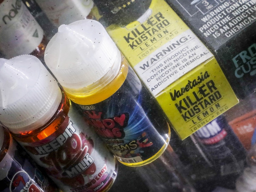 caption: Flavored vaping solutions stand displayed at a shop in New York City. Amid a mysterious health scare apparently caused by e-cigarettes, New York and Michigan have banned the sale of flavored vaping products, while Massachusetts has banned all of them for four months — moves that store owners say will hurt their bottom line.