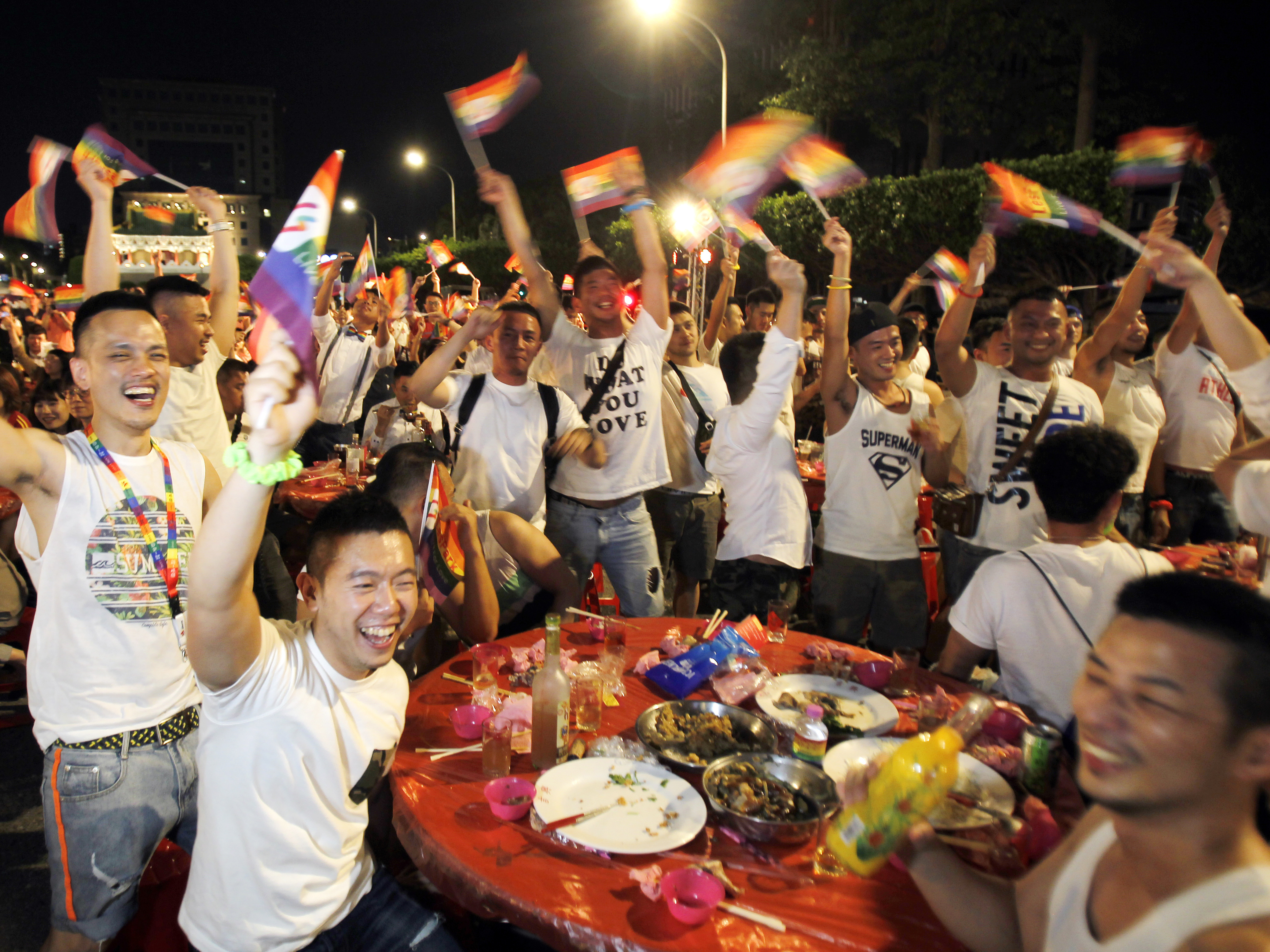 caption: Taiwanese same-sex couples cheer with supporters at a mass wedding banquet in Taipei, Taiwan.
