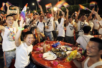 caption: Taiwanese same-sex couples cheer with supporters at a mass wedding banquet in Taipei, Taiwan.