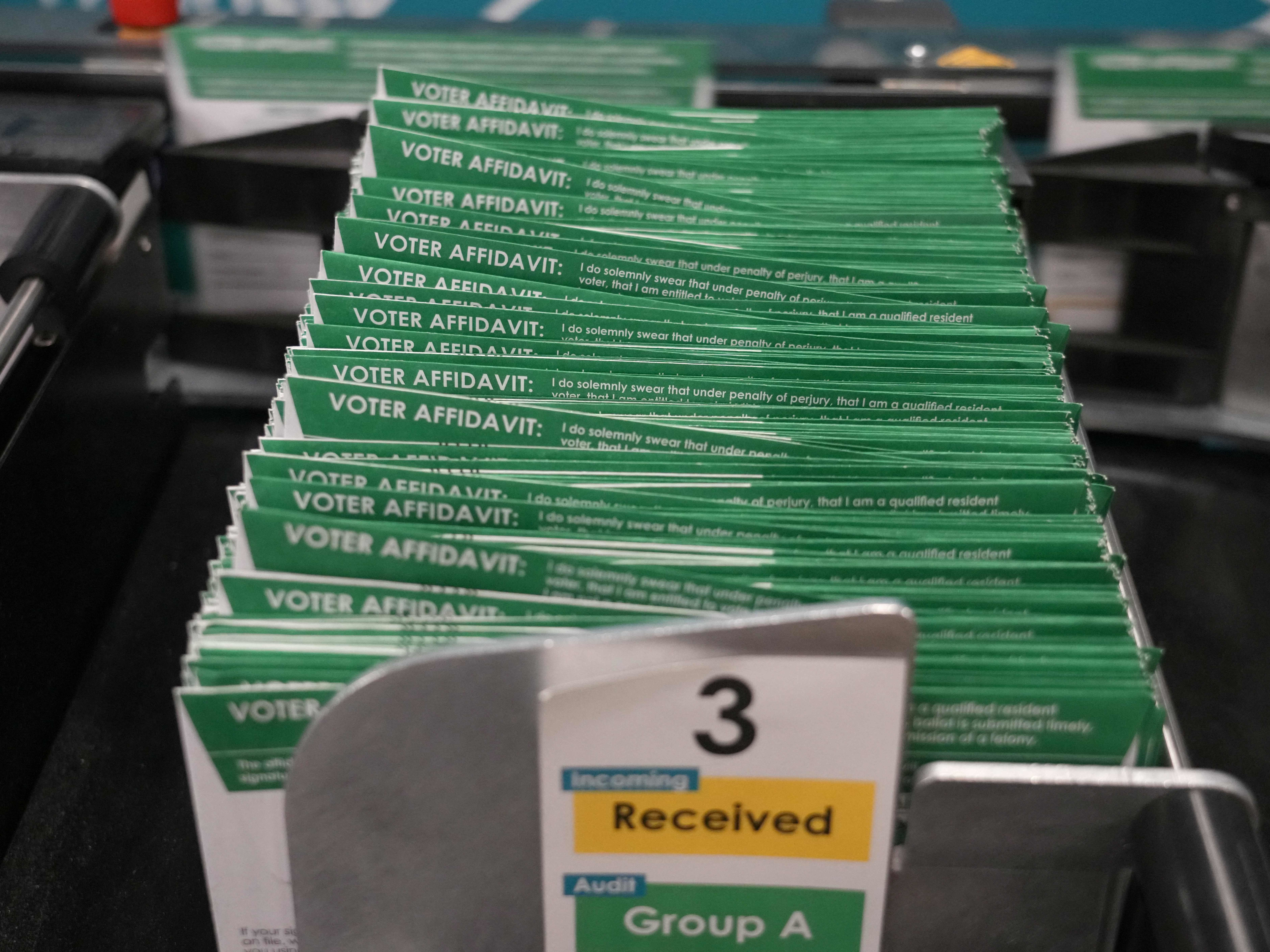 caption: Early voting ballots move through a ballot and signature verification machine at the Utah County election offices in Provo, Utah, on Friday.