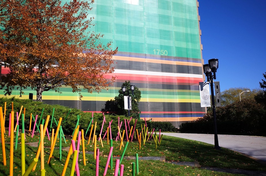 caption: Brightly colored buildings, like this one, have been covered in bright fabric to disguise their brutalist character. The pastel lawn spikes add stabs of color.