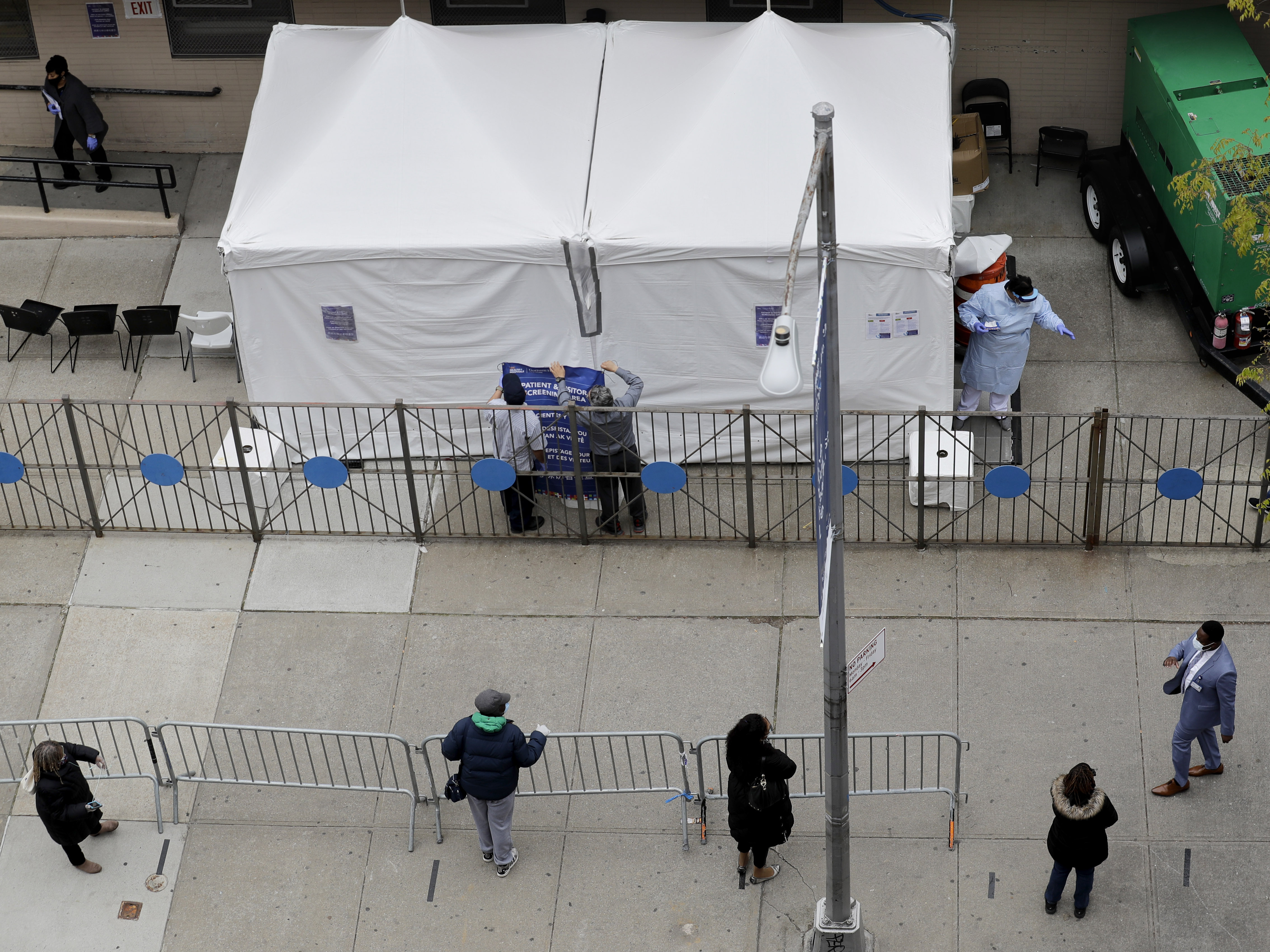 caption: People stand in line as they wait to get tested for COVID-19 at a just opened testing center in the Harlem section of New York on Monday.