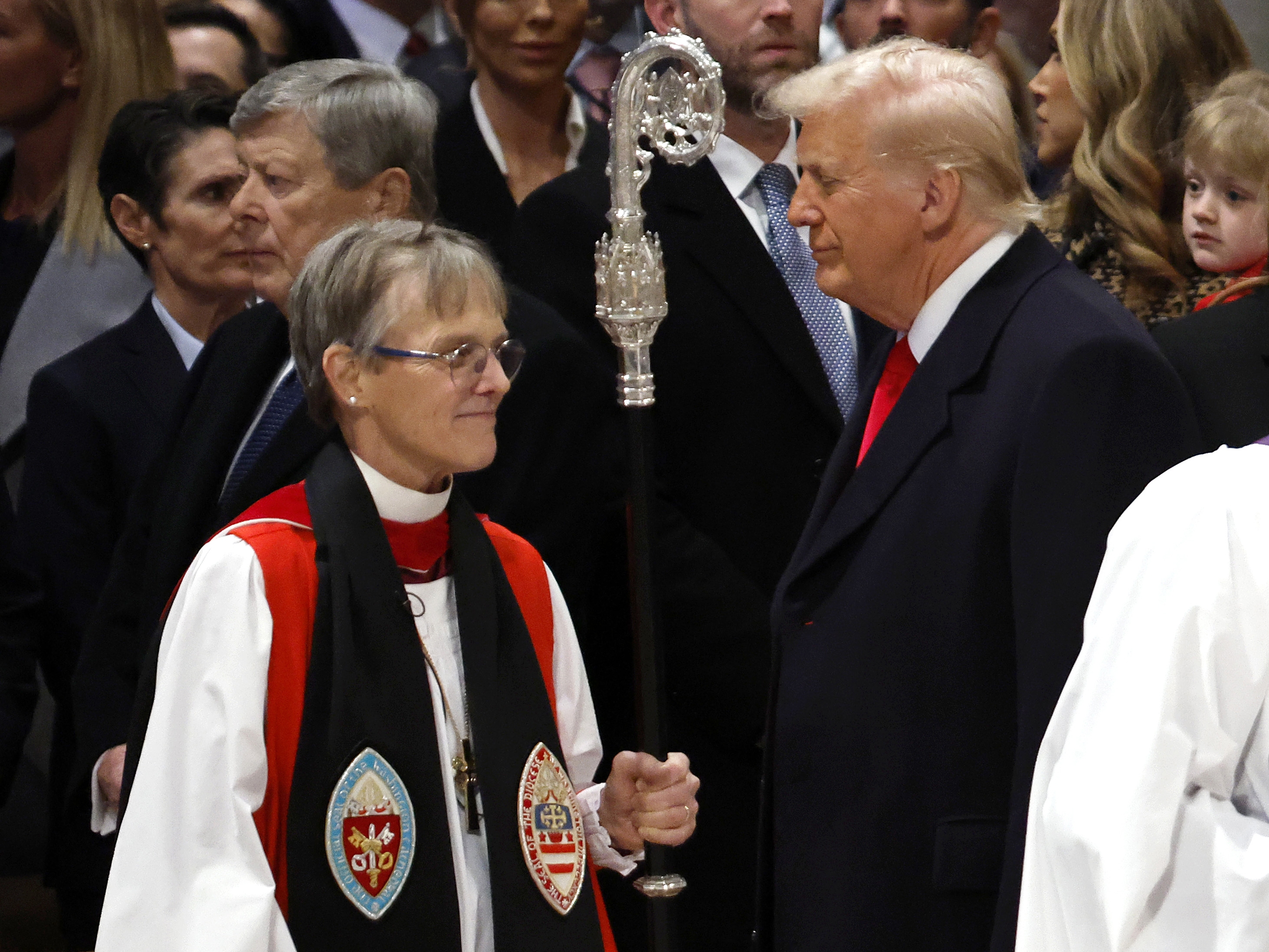 caption: Bishop Mariann Edgar Budde (left) arrives as President Trump looks on during the National Prayer Service at Washington National Cathedral on Jan. 21 in Washington, D.C.