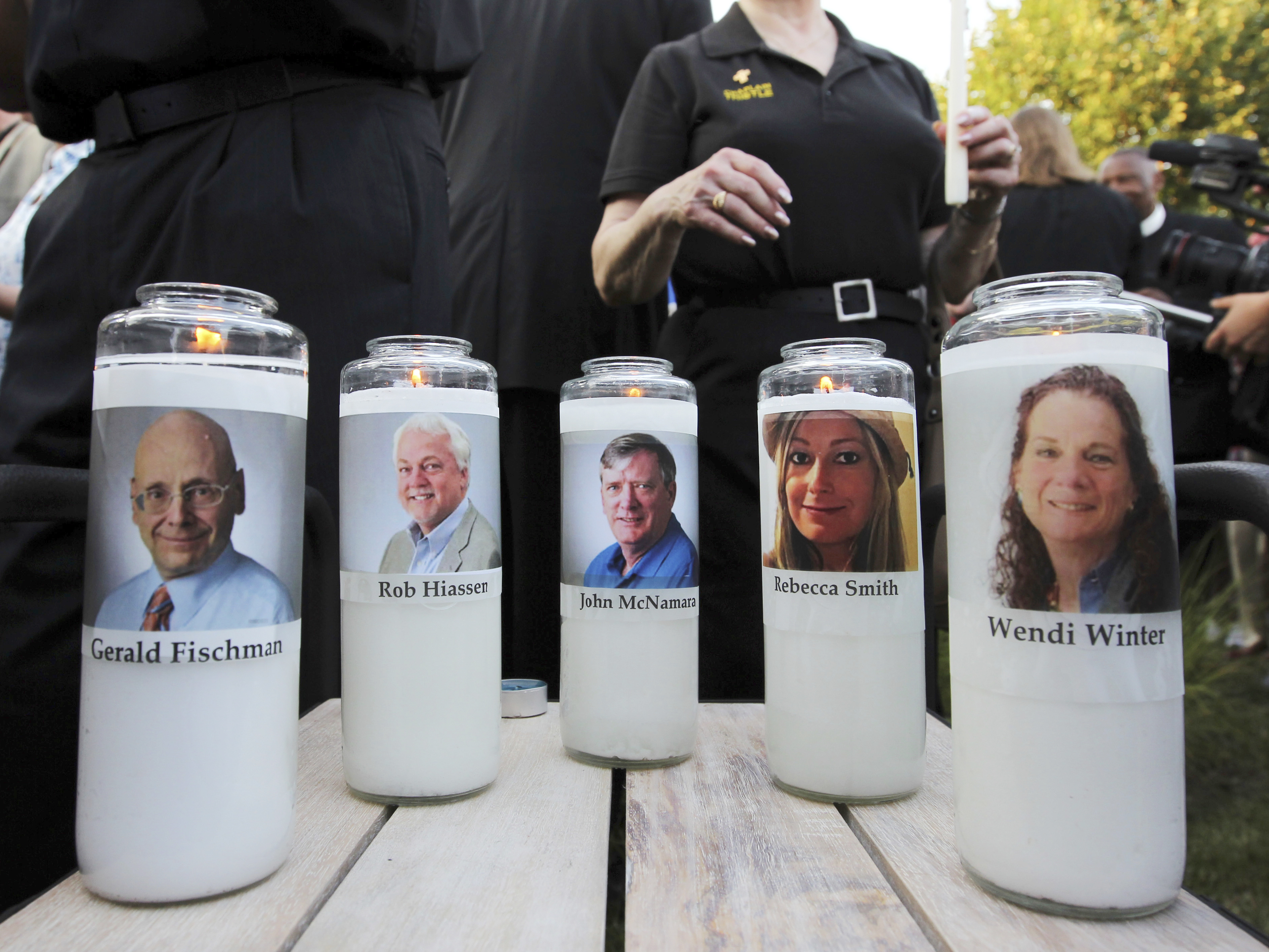 caption: Five employees of the Capital Gazette newspaper are honored across the street from where the the newsroom where they were killed in Annapolis, Md.