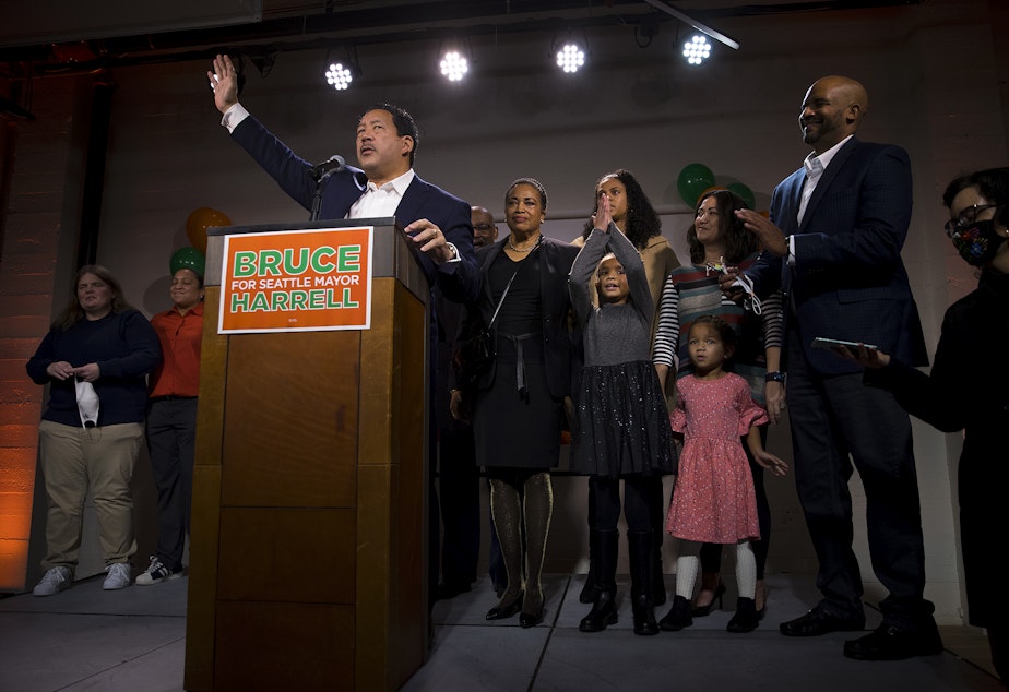caption: Bruce Harrell waves to supporters after speaking on stage surrounded by his family during an election night party on Tuesday, November 2, 2021, at Block 41 on Bell Street in Seattle. 