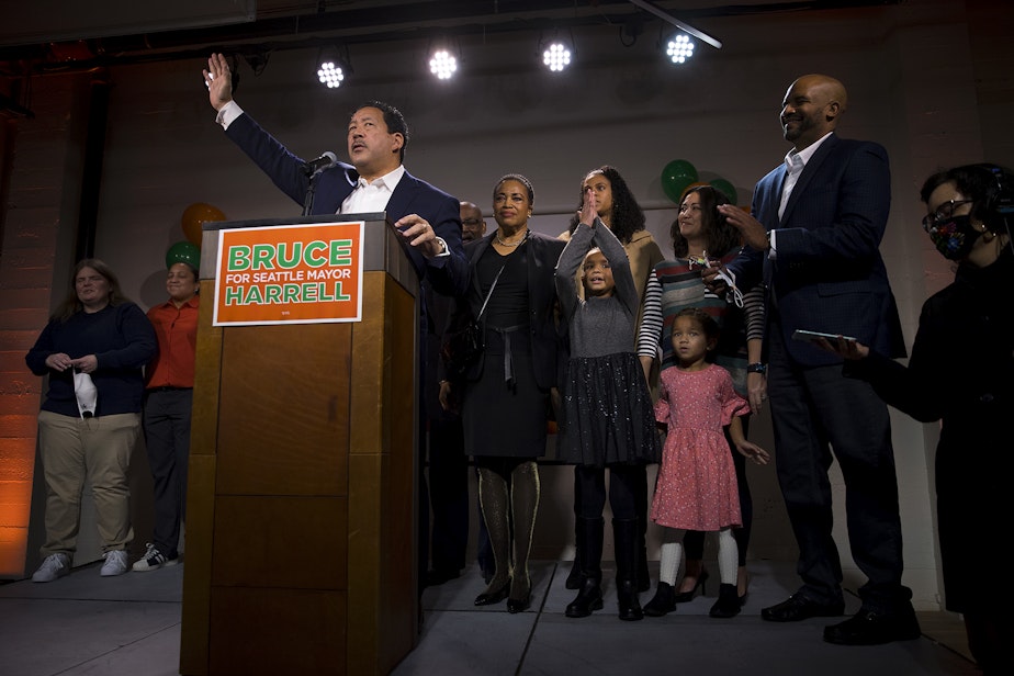 caption: Bruce Harrell waves to supporters after speaking on stage surrounded by his family during an election night party on Tuesday, November 2, 2021, at Block 41 on Bell Street in Seattle. 
