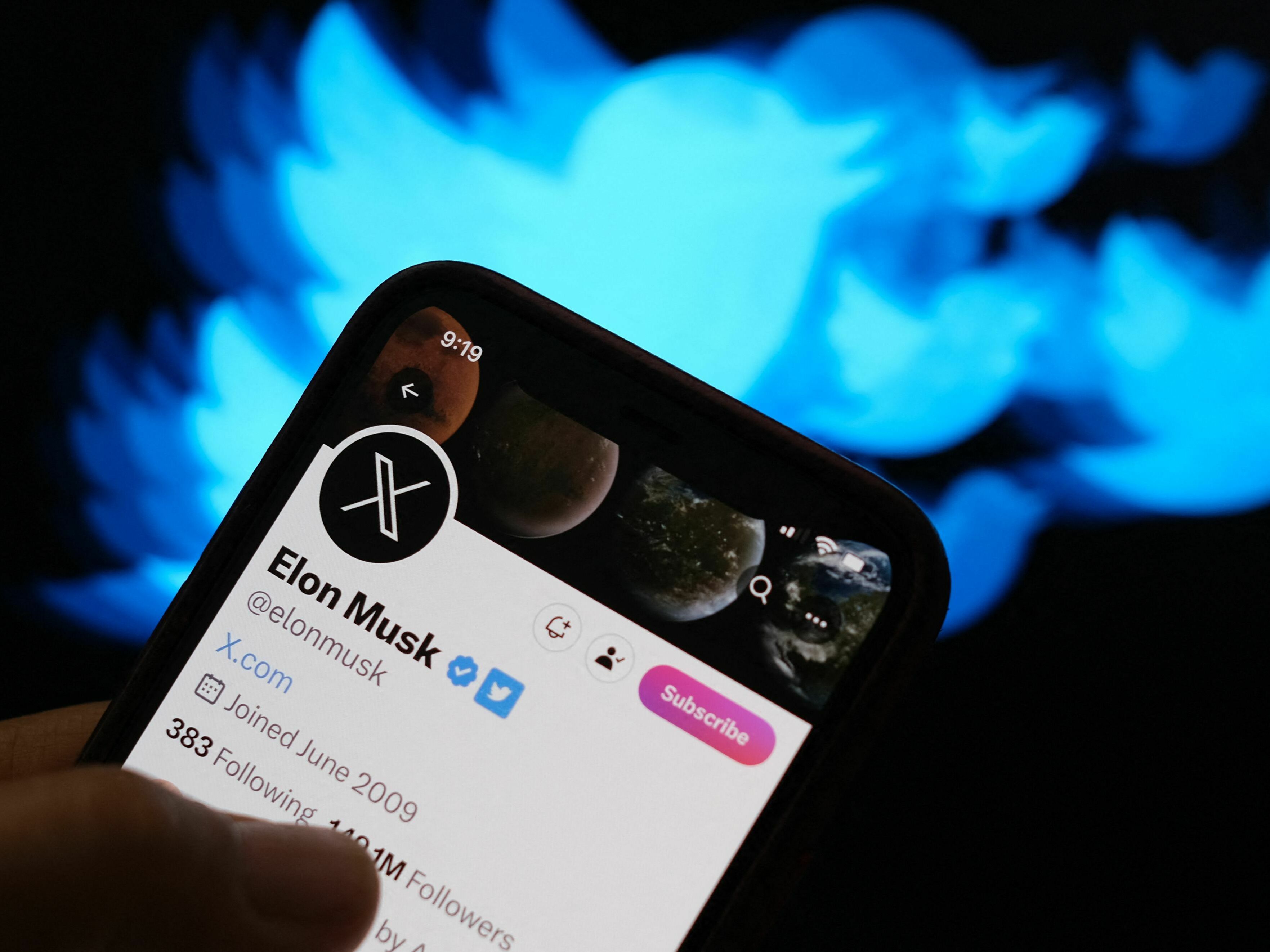caption: This illustration photo created on July 24 shows the Twitter bird logo in the background of the X account of Elon Musk.