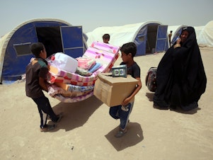 caption: Iraqis displaced from the city of Fallujah collect aid distributed by the Norwegian Refugee Council, which has been awarded this year's $2.5 million Conrad N. Hilton Humanitarian Prize.