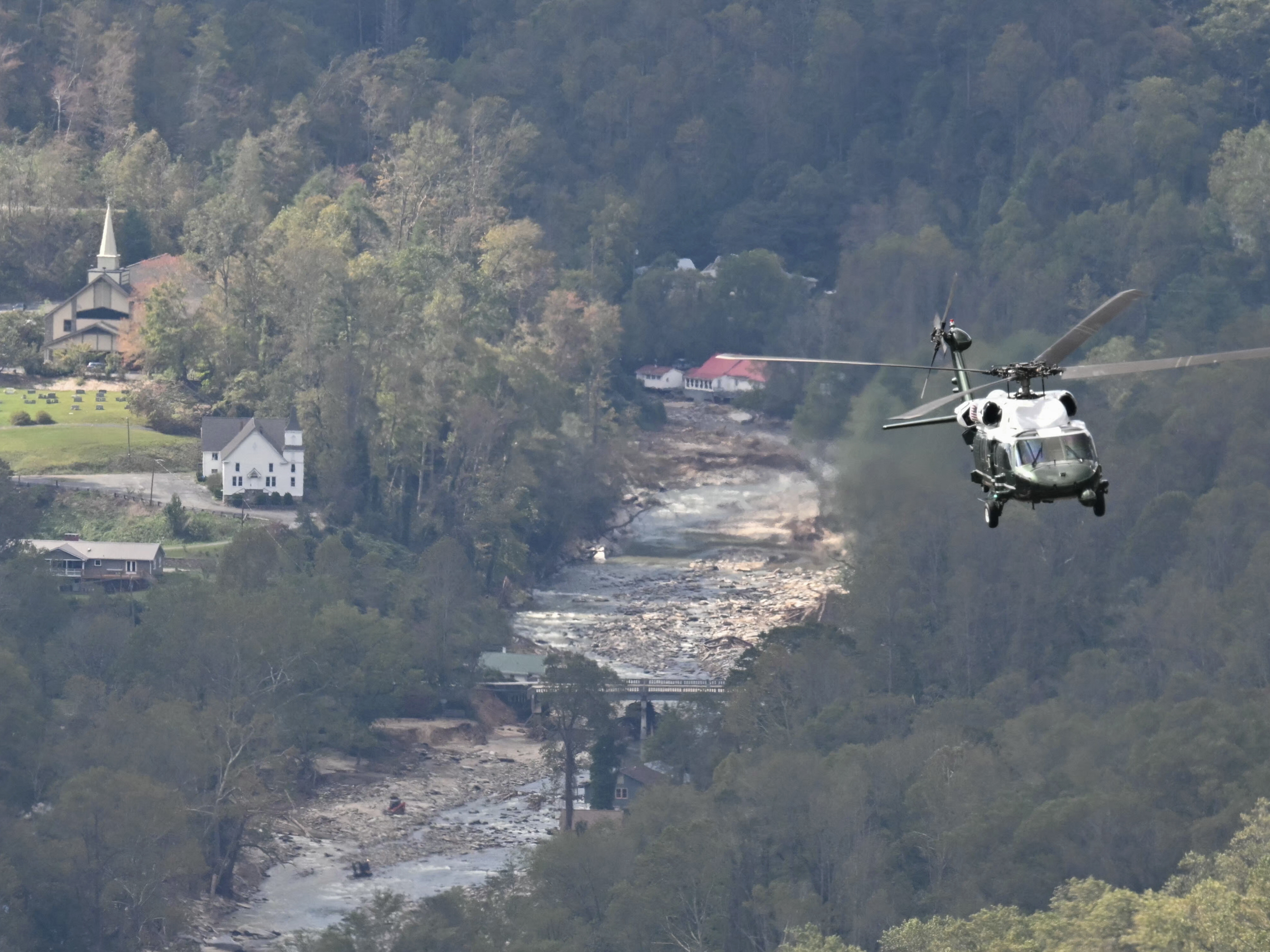 caption: Marine One, carrying President Biden, flies above a storm-impacted area near Asheville, N.C., on Wednesday. Biden was visiting North and South Carolina to survey damage after Hurricane Helene. Social media sites, especially X, were filled with politically charged rumors and conspiracy theories about the hurricane response.