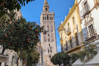 caption: The Giralda tower, part of the cathedral of Seville, viewed from Mateos Gago street.