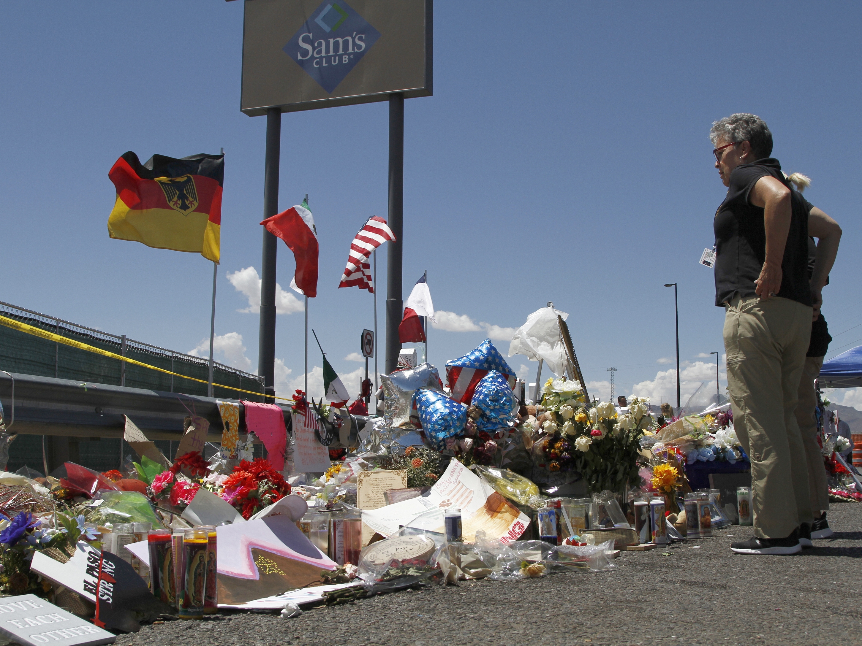 caption: In this Aug. 12, 2019 photo, mourners visit the makeshift memorial near the Walmart in El Paso, Texas.