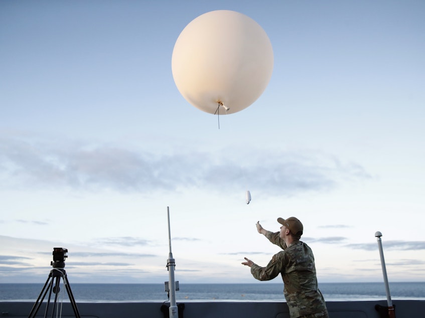 caption: A U.S. Air Force member releases a weather balloon from the deck of the U.S.S. Portland off the coast of Baja California, Mexico, in December 2022.