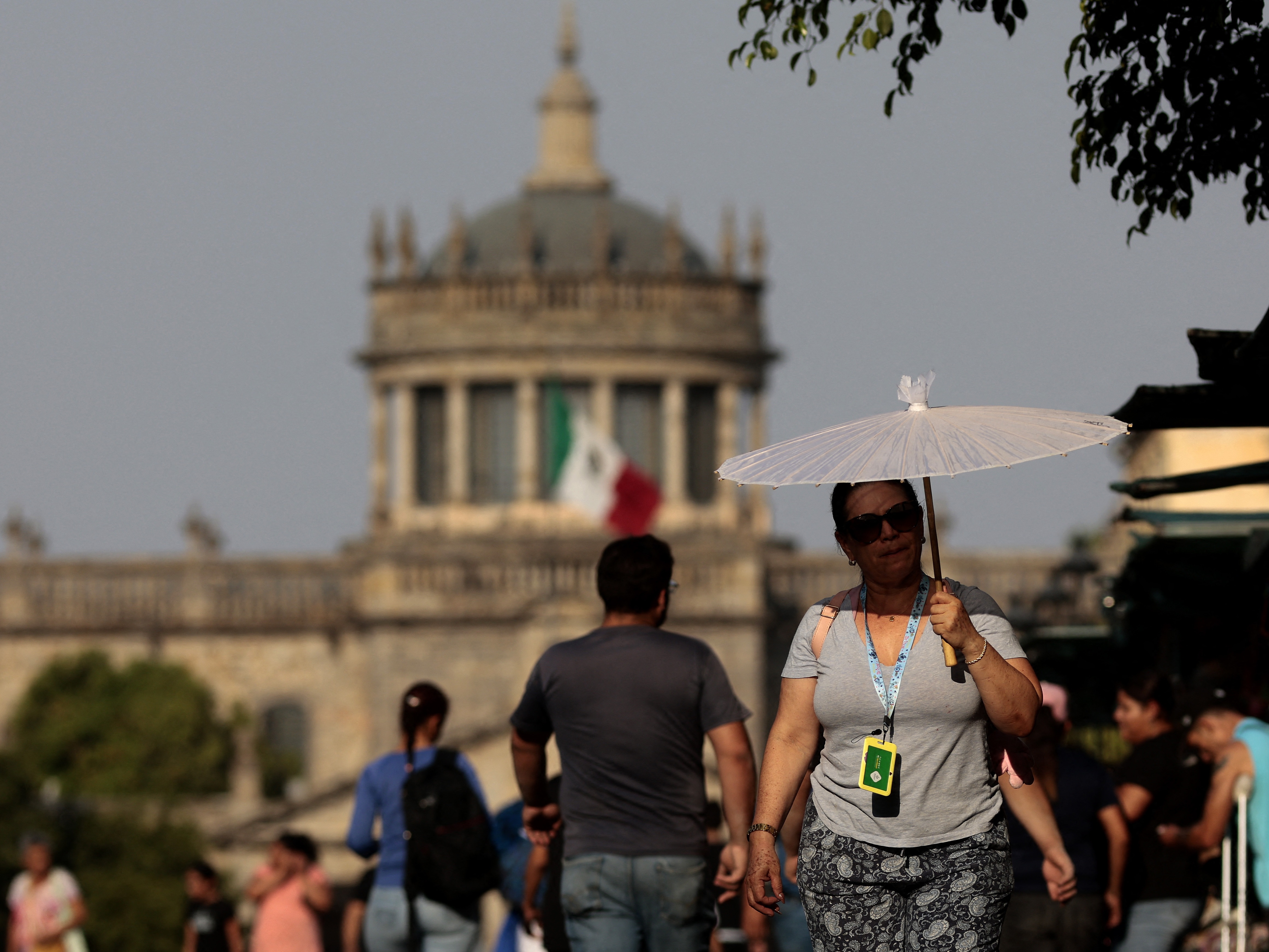 caption: People protect themselves from the sun during a heat wave in Guadalajara, Mexico, in 2024. Temperatures topped 110 degrees Fahrenheit across many parts of the country during the heat wave. A new study finds that young people are disproportionately at risk from extreme heat in the country.