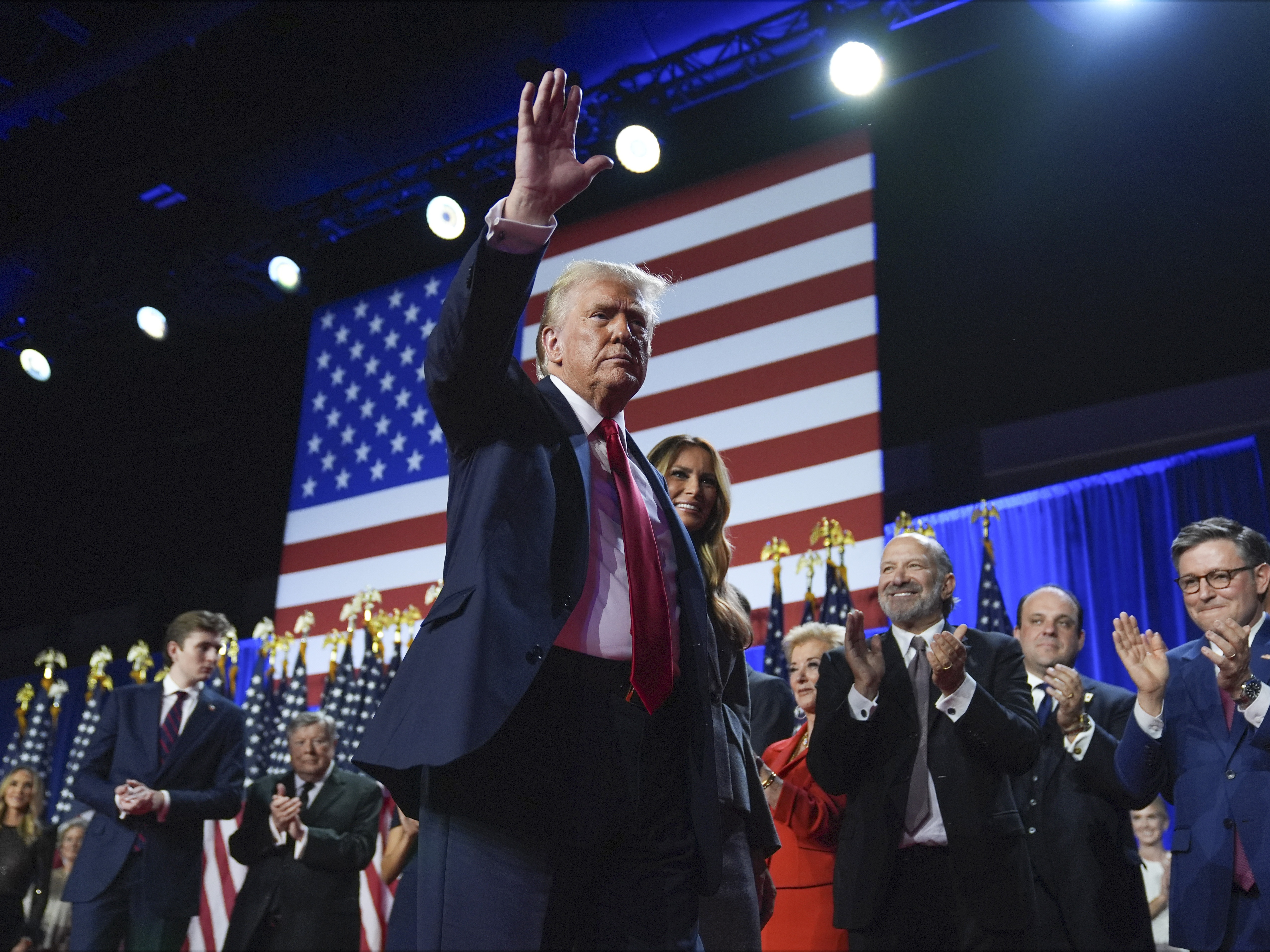 caption: Republican presidential nominee former President Donald Trump waves as he walks with former first lady Melania Trump at an election night watch party at the Palm Beach Convention Center, Wednesday, Nov. 6, 2024, in West Palm Beach, Fla.
