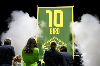 caption: Former Seattle Storm guard Sue Bird, in green, stands with her family as her jersey number is lifted into the rafters during a ceremony following a WNBA basketball game between the Storm and the Washington Mystics, Sunday, June 11, 2023, in Seattle. 