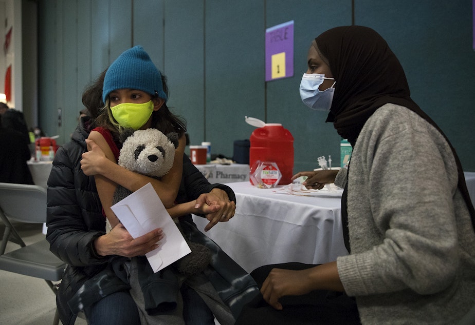caption: Tejal Armes, 9, holds onto a stuffed panda bear shortly before registered nurse Iman Yunis with the Othello Station Pharmacy administers a Covid-19 vaccine on Wednesday, November 10, 2021, at Thurgood Marshall Elementary School in Seattle. 