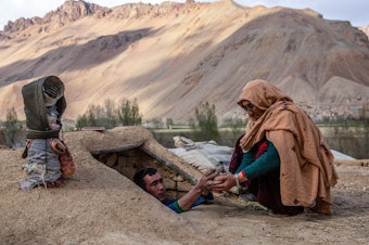 caption: Roqia Qasqari, right, who lives in Gero village in Afghanistan's Bamyan Province, inspects potatoes stored from a previous harvest. Snow was scarce over the winter, raising fears of a severe drought in 2021.
