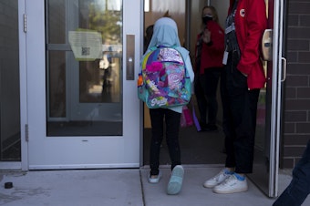 caption: Second and third-grade students enter Wing Luke Elementary school on the first day, Wednesday, September 1, 2021, along Kenyon Street in Seattle.