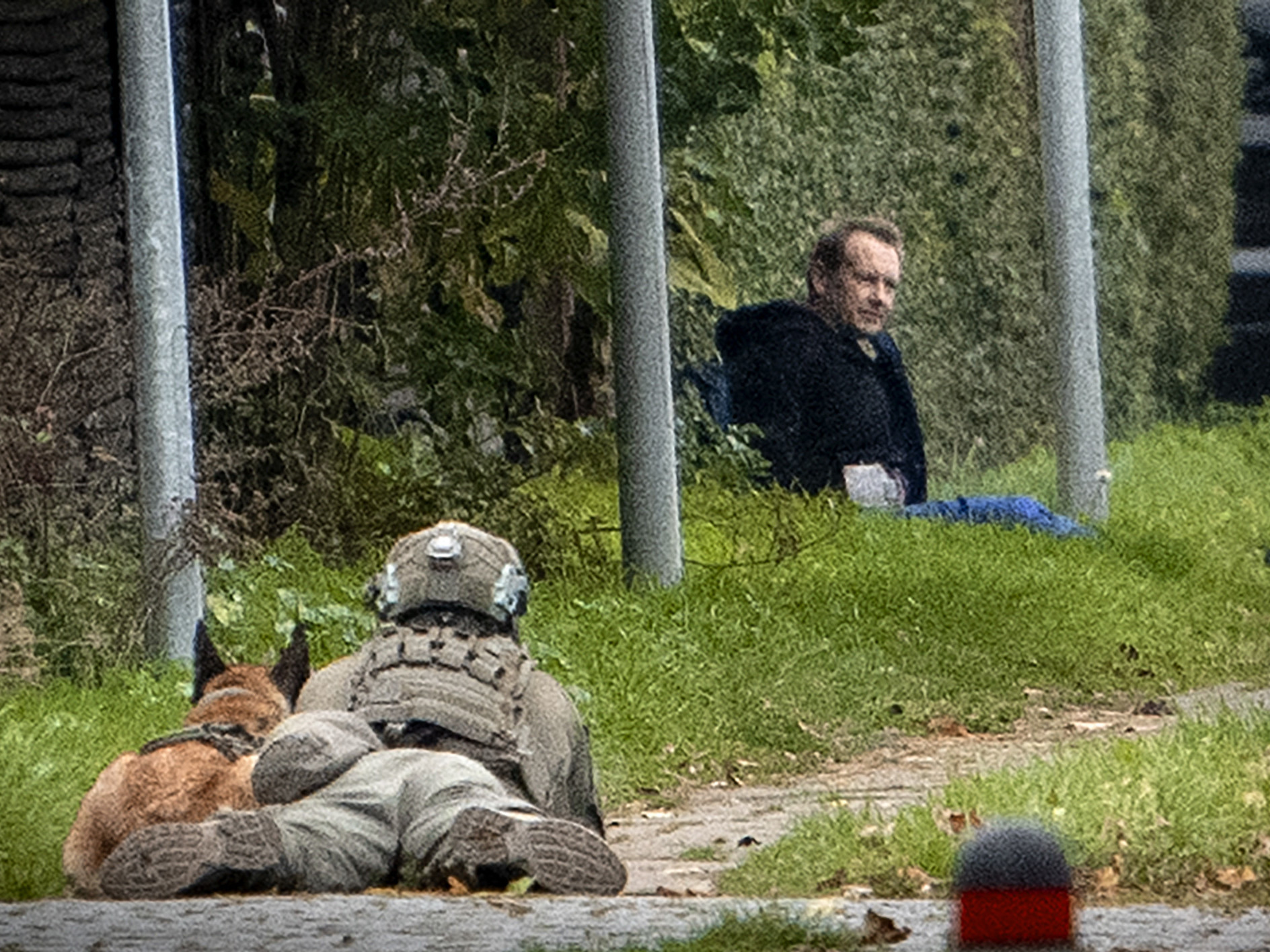 caption: A police marksman and his dog observes convicted killer Peter Madsen threatening police with detonating a bomb while attempting to break out of jail Tuesday in Albertslund, Denmark.