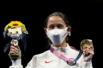 caption: Gold medalist Lee Kiefer of the United States shows her medal and victory bouquet during the medal ceremony for the women's individual foil final competition on Sunday at the Summer Olympics.