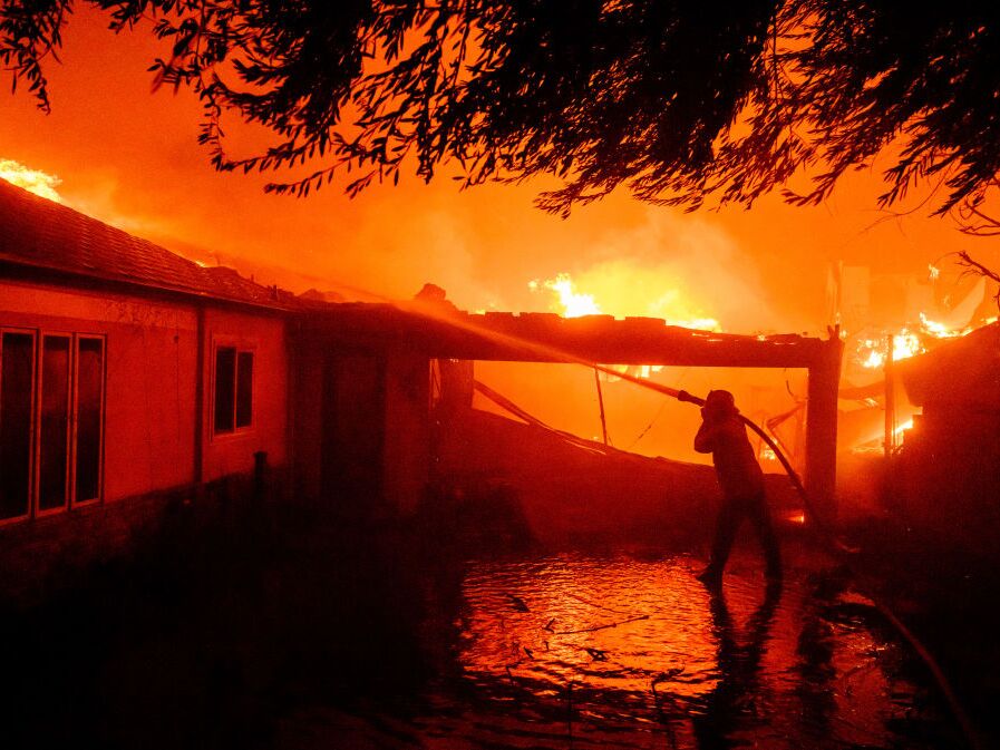 caption: A firefighter douses flames during the Eaton Fire in Pasadena, Calif., on Jan. 8.