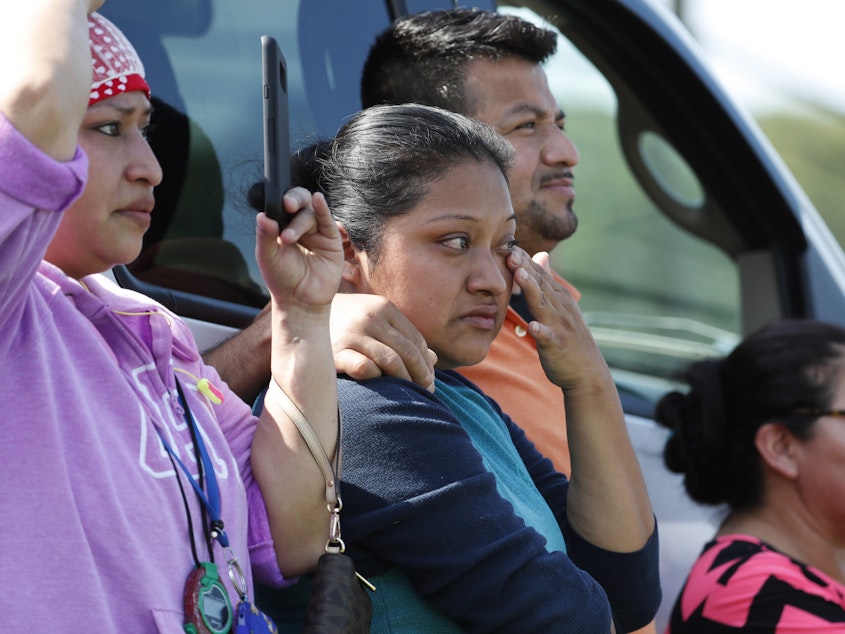 caption: Friends, co-workers and family watch as U.S. immigration officials raid the Koch Foods Inc. plant in Morton, Miss., on Wednesday.