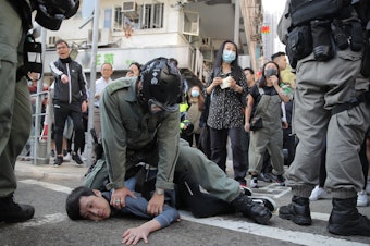 caption: A protester is detained in Hong Kong on Monday. Hong Kong is in the sixth month of protests that began in June over a proposed extradition law and have grown to include other grievances.
