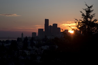 caption: The sun sets behind downtown Seattle.