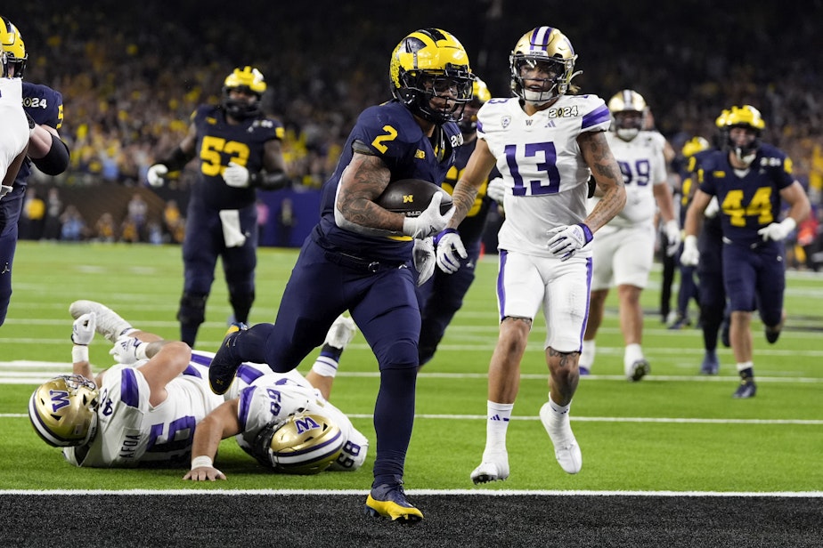 caption: Michigan running back Blake Corum scores against Washington during the second half of the national championship NCAA College Football Playoff game Monday, Jan. 8, 2024, in Houston. 