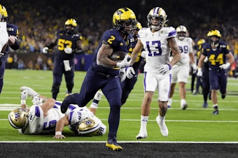 caption: Michigan running back Blake Corum scores against Washington during the second half of the national championship NCAA College Football Playoff game Monday, Jan. 8, 2024, in Houston. 