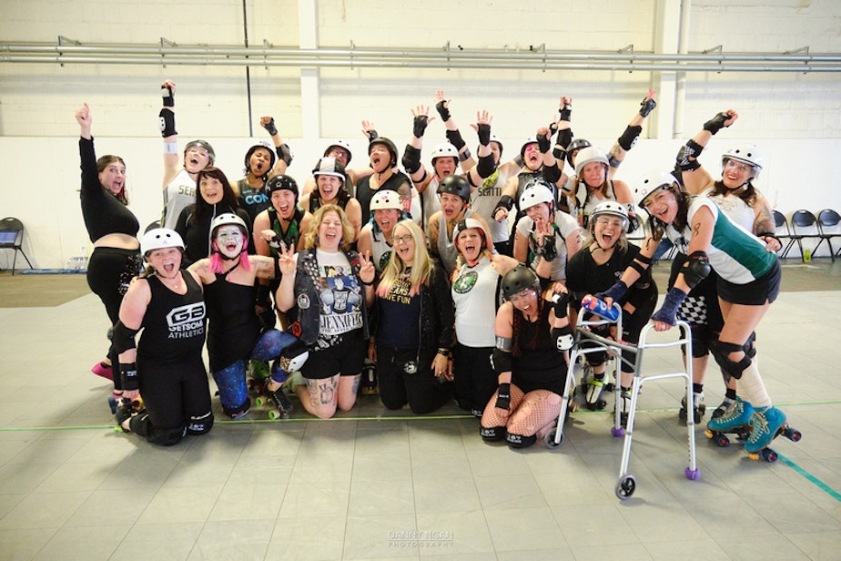 caption: The alumni skaters at Rat City Roller Derby's 20th Anniversary celebration cheer after finishing their exhibition bout.