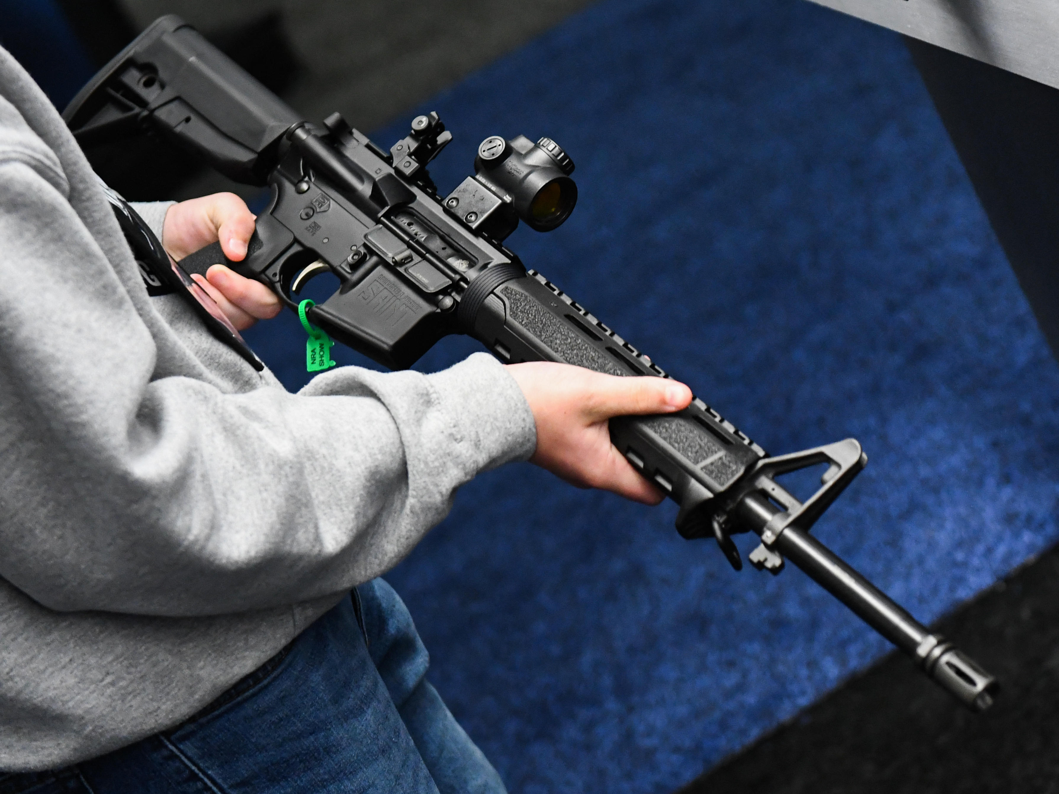 caption: An attendee holds a Springfield Armory SAINT AR-15-style rifle displayed during the National Rifle Association Annual Meeting in Houston in 2022.