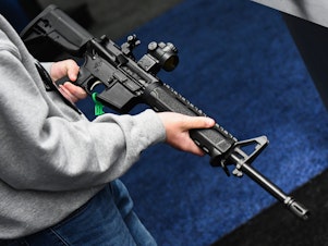 caption: An attendee holds a Springfield Armory SAINT AR-15-style rifle displayed during the National Rifle Association Annual Meeting in Houston in 2022.