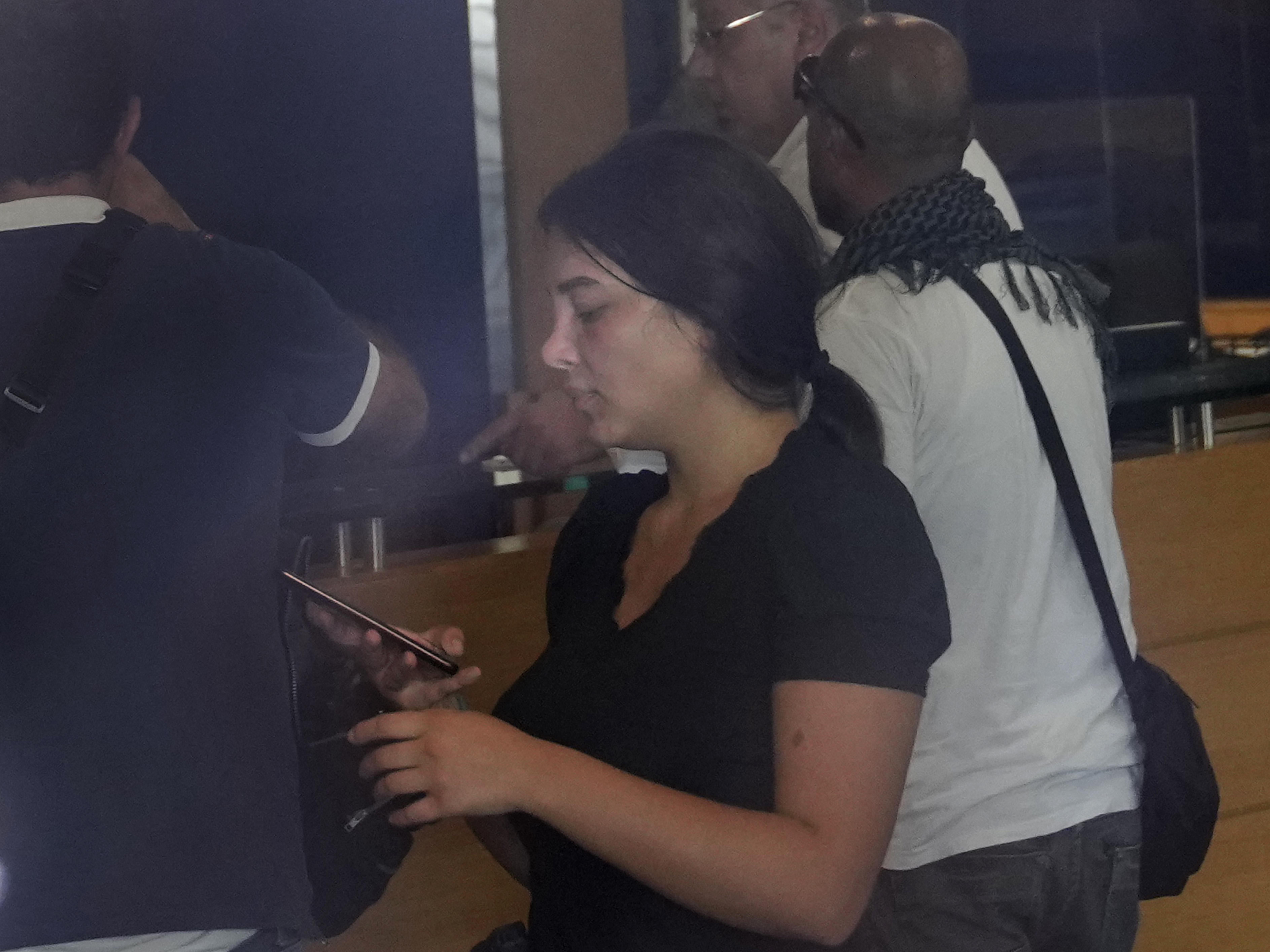 caption: Sali Hafez (center), accompanied by activists, looks at her phone on Wednesday after breaking into a BLOM Bank branch in Beirut, Lebanon, brandishing what she later said was a toy pistol and taking $13,000 from her trapped savings account.