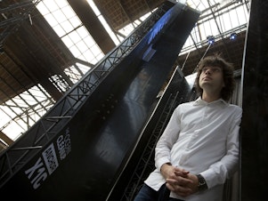 caption: Dutch innovator Boyan Slat poses for a portrait next to the anchors of his plastic collecting system in 2017. The trash collection device deployed to corral plastic litter floating is not capturing any garbage.