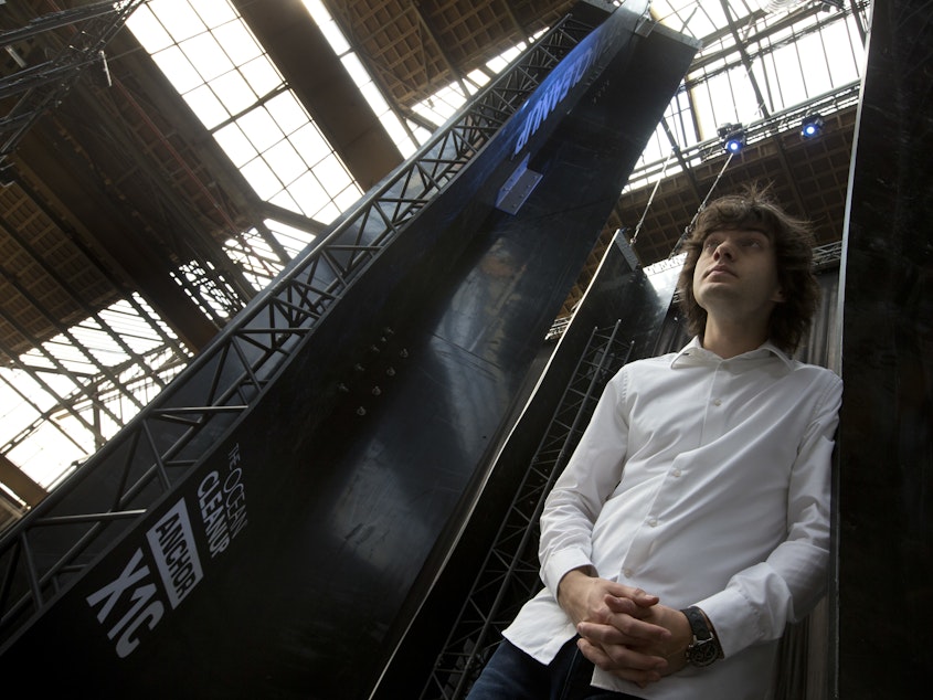 caption: Dutch innovator Boyan Slat poses for a portrait next to the anchors of his plastic collecting system in 2017. The trash collection device deployed to corral plastic litter floating is not capturing any garbage.