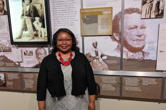 caption: LaNesha DeBardelaben, president and CEO of the Northwest African American Museum stands in front of a display about slavery on Thursday, June 16, 2022