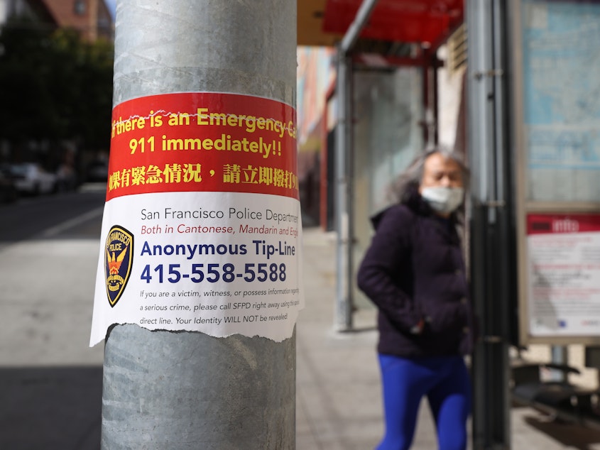 caption: A sign posted in San Francisco's Chinatown neighborhood on March 8 encourages people to call a police tip line if they witness a crime.