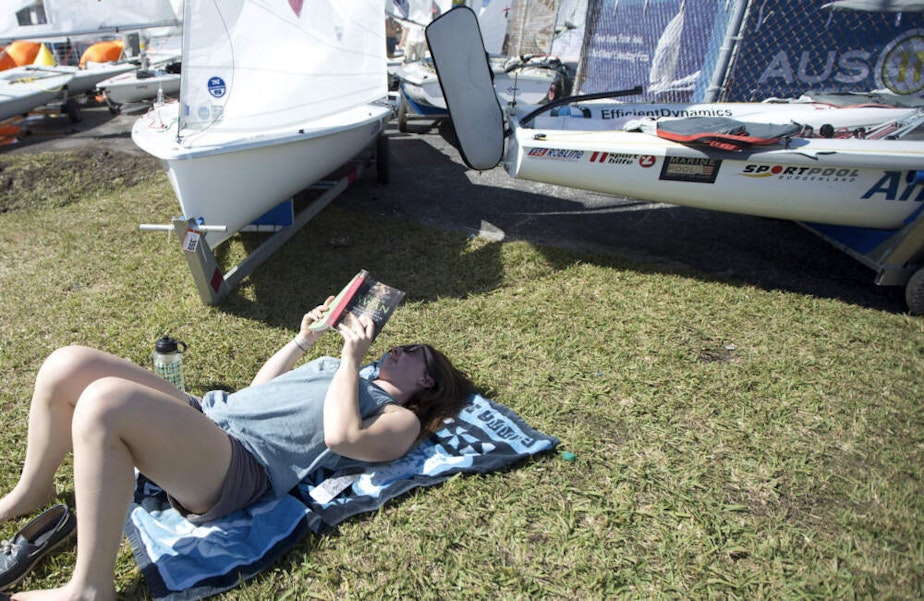 caption: Rae-Anne Norwood, from Canada, lays in the sun reading a book. (J Pat Carter/AP)