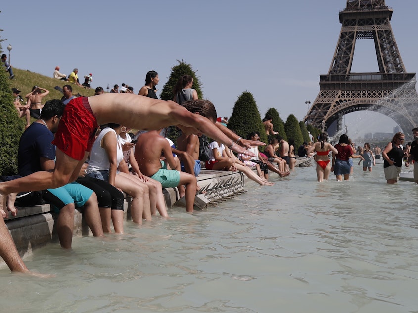 caption: A boy jumps into the water of the Trocadero Fountain in Paris on Friday, to find relief from the heat wave.
