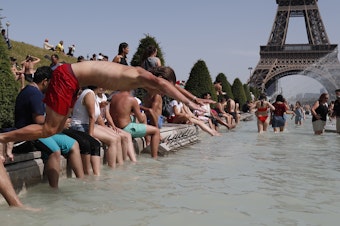 caption: A boy jumps into the water of the Trocadero Fountain in Paris on Friday, to find relief from the heat wave.